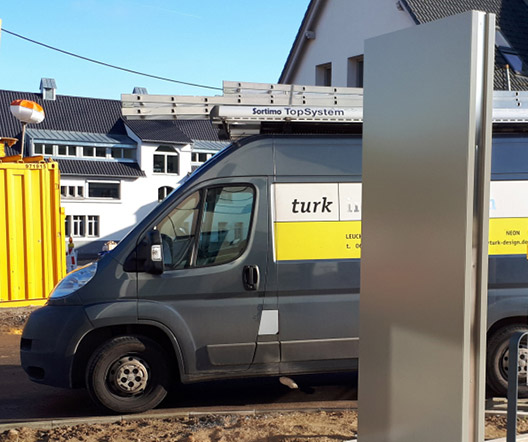 Rückansicht Werbe-Stele, dahinter sichtbar Fahrzeug Tomas Turk