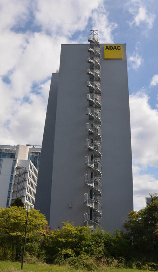 Rückansicht eines Hochhauses mit prominentem ADAC-Logo und Wendeltreppe.