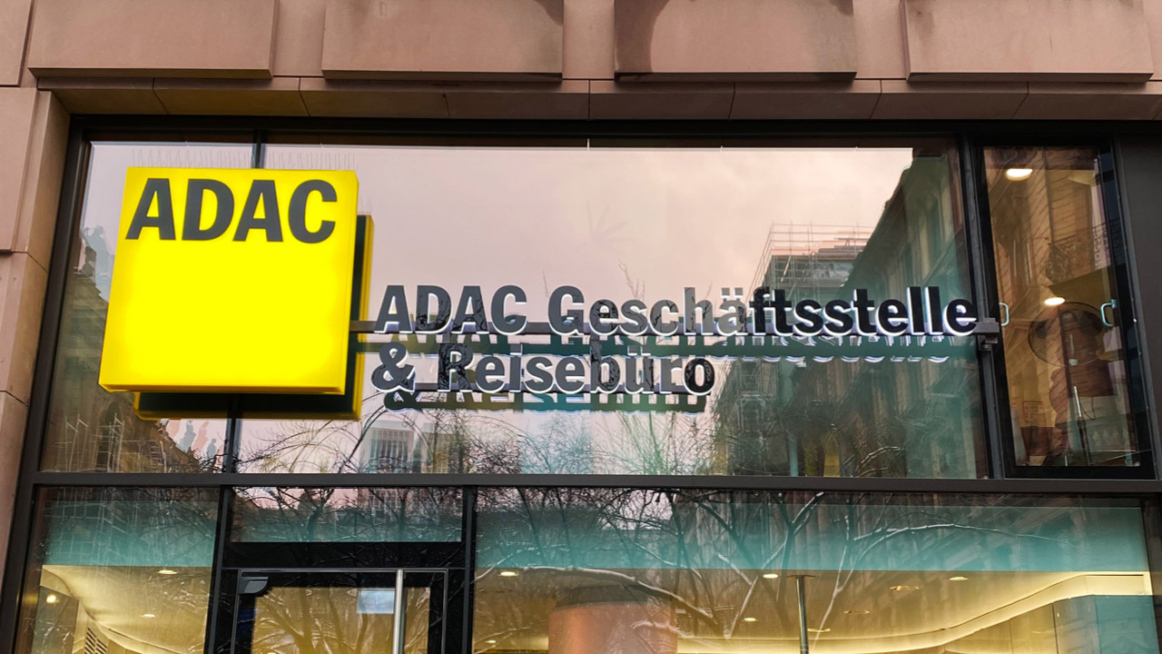 Außenansicht der ADAC-Geschäftsstelle und des Reisebüros mit einem großen gelben ADAC-Logo und den Einzelbuchstaben auf der Glasfläche über dem Eingang