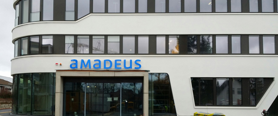 Frontansicht des Bürogebäudes mit der Leuchtschrift „Amadeus“ über dem Eingang