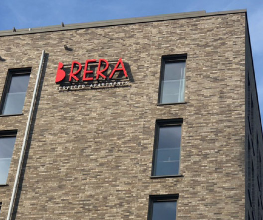 Brera-Logo und Schriftzug „Serviced Apartments“ auf der Fassade eines Hotels.