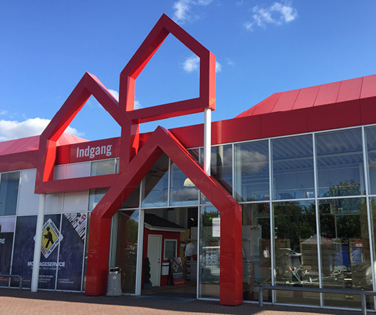 Eingangsbereich eines BAUHAUS-Marktes mit rotem Fassadendesign und großem Schaufenster.