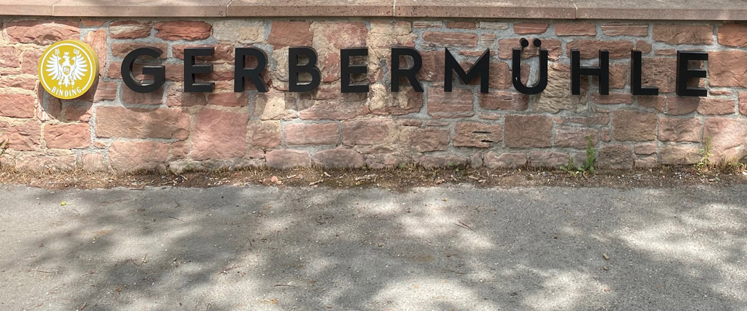 Gerbermühle Schriftzug auf einer Steinmauer in Frankfurt, frontal aufgenommen an einem sonnigen Tag.