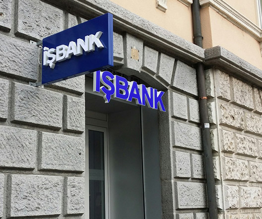 Außenansicht einer IŞBANK-Filiale, das blaue Logo auf einer klassischen Steinmauer angebracht.