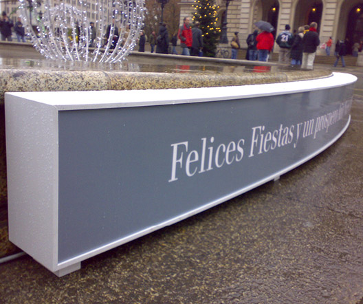 Nahaufnahme des spanischen Neujahrsgrußes von UBS und WISAG auf einem beleuchteten Schild vor dem Brunnen an der Alten Oper in Frankfurt.