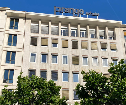 Leuchtschrift „Prange Schuhe“ auf dem Dach eines hellen Gebäudes in der Frankfurter Innenstadt bei Tageslicht.