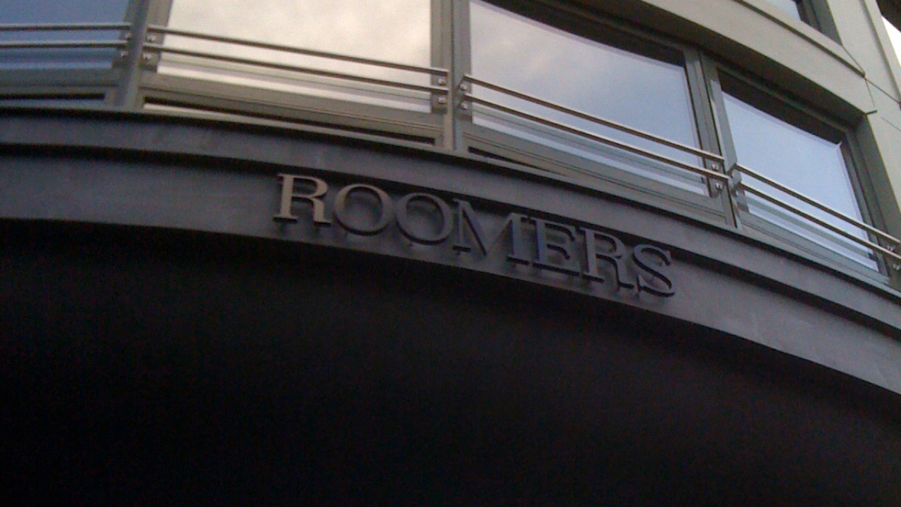 Logo des Roomers Hotel in Frankfurt unter einer Fensterfront.