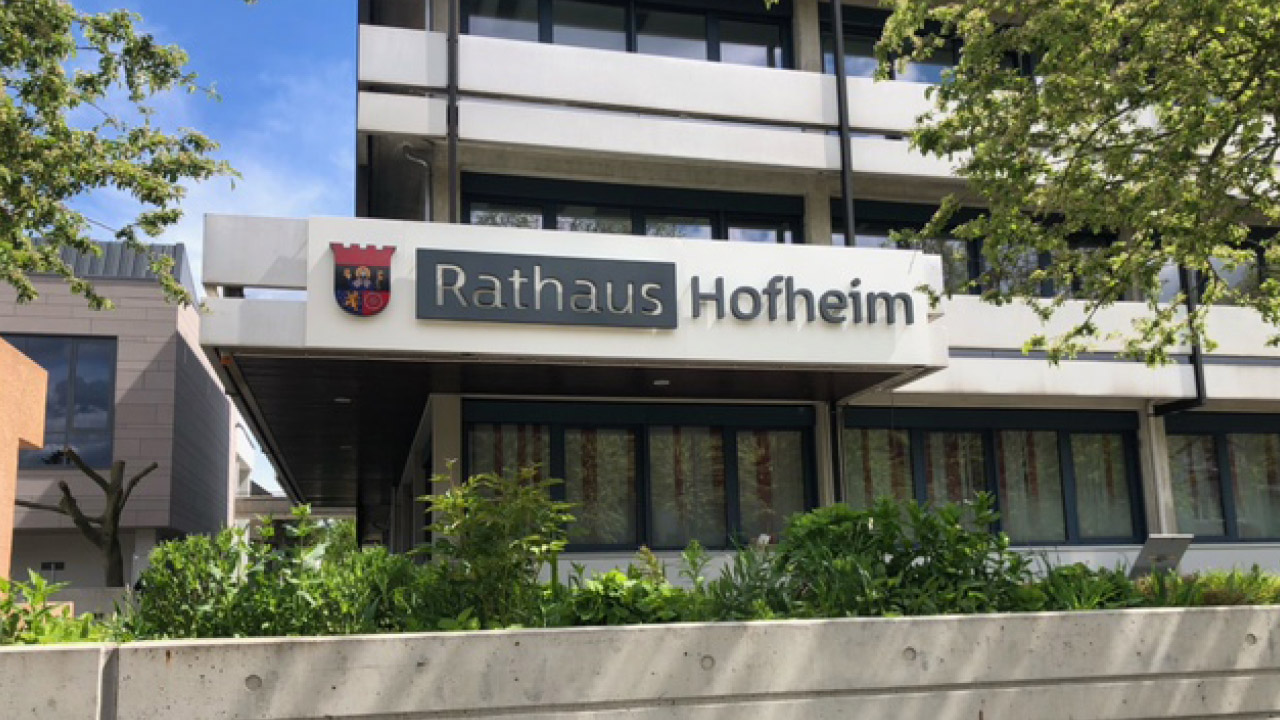 Außenansicht des Rathauses Hofheim mit Schild im Vordergrund.