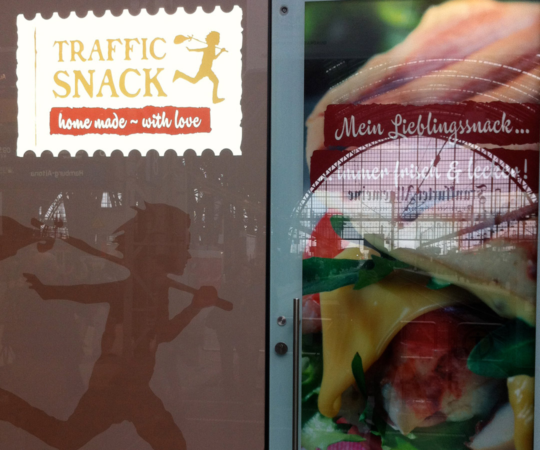 Fensterbeklebung mit der Aufschrift „Traffic Snack“ und der Abbildung eines belegten Sandwiches.