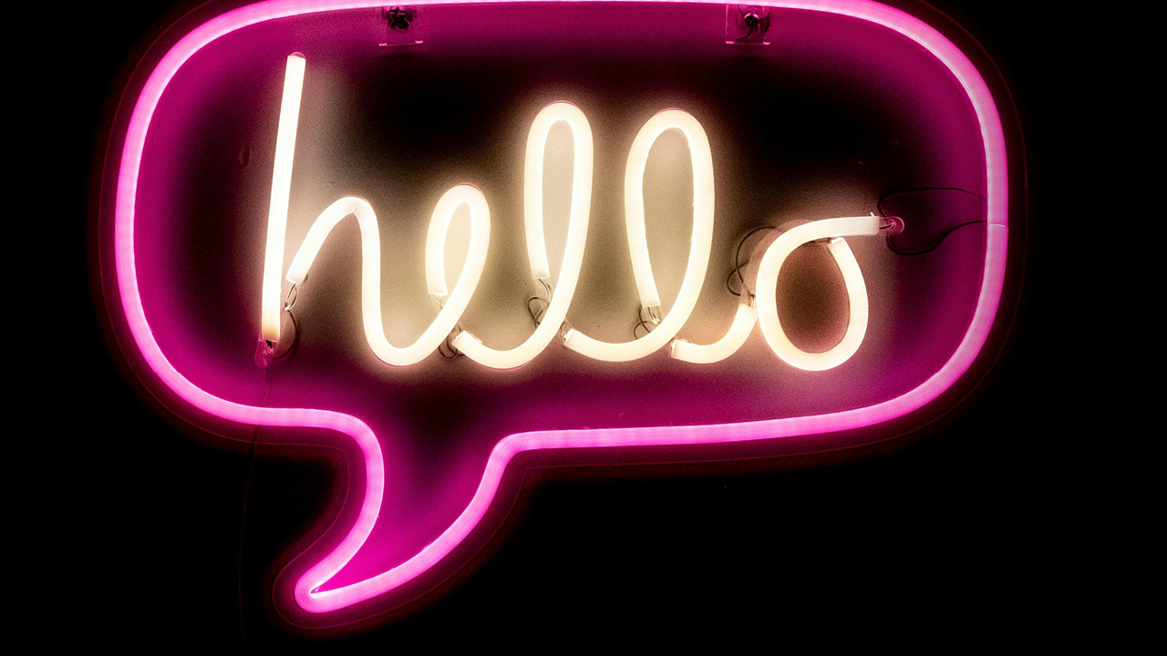 Neon-Schriftzug „hello“ in einer Sprechblase in den Farben weiß und rosa